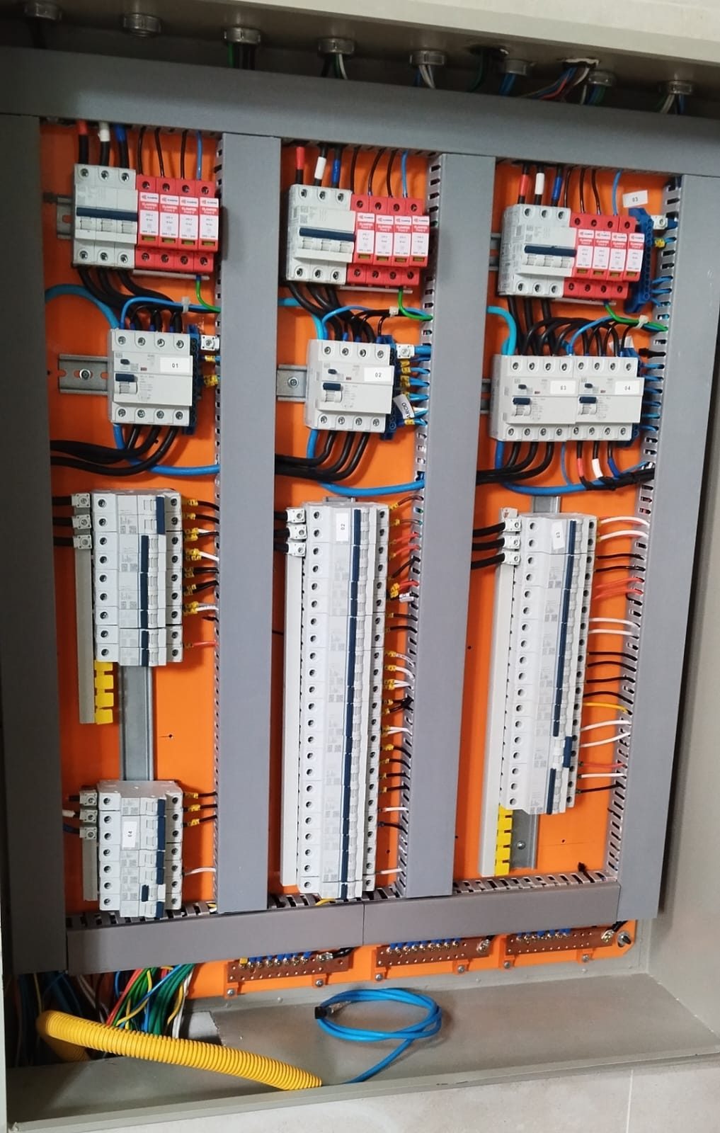 Quadro de distribuição industrial com dispositivos de proteção contra surtos, disjuntores diferenciais residuais e disjuntores em trilho DIN, com condutores identificados e organizados