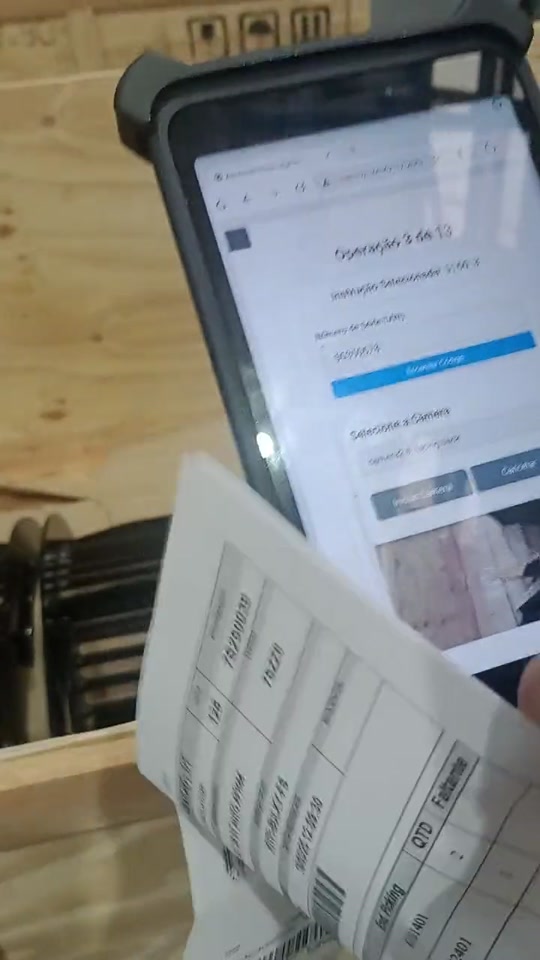 Tablet exibindo a instrução da operação 3 de 13 e o campo de número de série, ao lado da etiqueta e do engradado de madeira sendo embalado